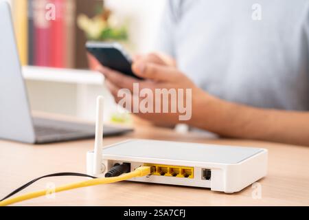 Nahaufnahme von Mannhänden, die mehrere Geräte mit Breitband-Router im Vordergrund verwenden Stockfoto