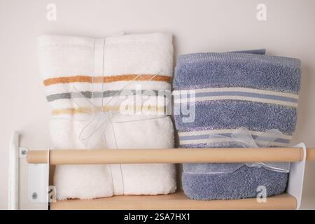 Weiche, ordentlich gefaltete Handtücher auf einem Holzregal im Badezimmer Stockfoto