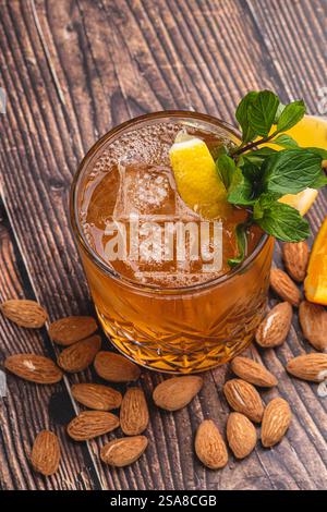Luxuriöser Cocktail mit Mandeln und Zitrusfrüchten in Kristallglas auf Holztisch Stockfoto