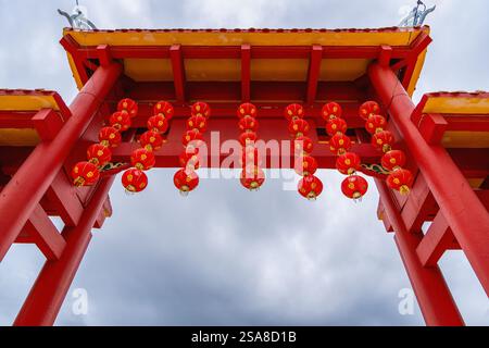 Ein roter Tempelbogen mit roten Laternen an einem bewölkten Himmel im Peak Nam Toong Tempel in Sabah, Malaysia. Stockfoto