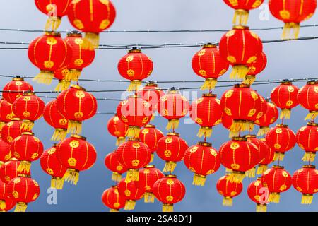 Rote chinesische Laternen hängen in Reihen vor einem bewölkten Himmel Hintergrund. Stockfoto