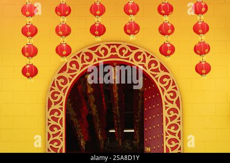 Ein Tempeleingang mit kunstvollen Schnitzereien, dekoriert mit hängenden roten Laternen. Stockfoto
