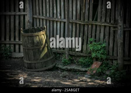 Altes Holzfass neben einem Holzzaun auf dem Land Stockfoto