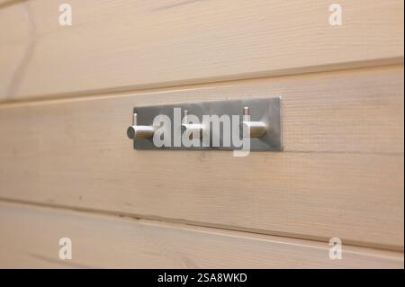 Wandbügel aus Metall an einer Holzwand. Praktisches Aufbewahrungskonzept. Stockfoto