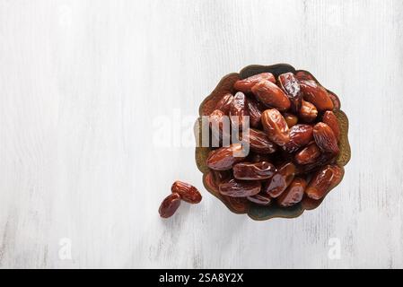Schüssel mit Datteln auf weißem hölzernem Hintergrund. Draufsicht. Stockfoto