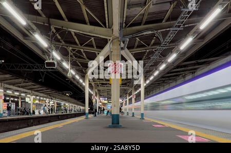Langzeitbelichtung Nachtsicht vom Ende eines Bahnsteigs am Bahnhof Asagaya im Westen Tokios, mit der Unschärfe eines vorbeifahrenden Zuges auf der rechten Seite Stockfoto