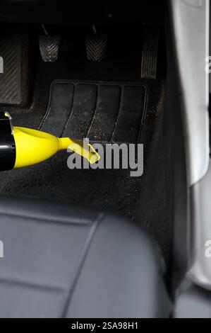 Professionelle Reinigung von schmutzigem Fahrzeugboden mit Staubsauger im professionellen Detailstudio. Reinigen des Fahrzeuginnenraums von Schmutz, Staub und Sand. Vertikal. Stockfoto