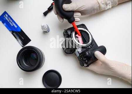 Reinigen des Kamerasensors mit einem Gebläse für Bürogeräte und Elektronik von Verunreinigungen. Reinigung und Pflege des Kamerasensors. Das Konzept Stockfoto
