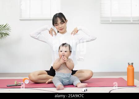 Mutter trainiert, während ihr Baby auf der Matte spielt Stockfoto