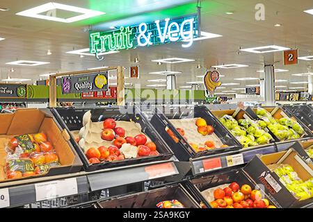 Ein Schild mit Obst- und Gemüsebeleuchtung an der Decke über Kunststoffkisten mit roten und grünen Äpfeln zum Verkauf oder Großpackungen Essex England UK Stockfoto