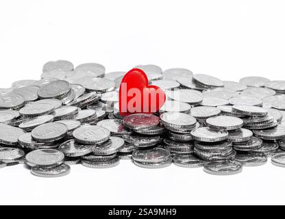 Rotes Herz auf Silbermünzen. Isoliert auf weiß. Liebe oder Geld, Liebe und Geld. Vermögen oder Sparsamkeit Stockfoto