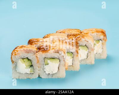 Studio-Fotografie von Philadelphia Roll mit samtigem Frischkäse und Gurke, gewickelt in perfekt gewürzten Sushi-Reis und frischem unagi geräucherten Aal. Isoliert auf hellblauem Hintergrund Stockfoto