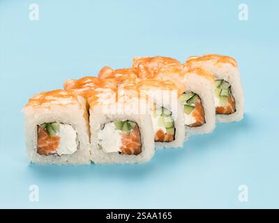 Studio-Fotografie von Philadelphia Roll mit samtigem Frischkäse, Gurke und Lachs, verpackt in perfekt gewürzten Sushi-Reis und frischen Garnelen. Isoliert auf hellblauem Hintergrund Stockfoto
