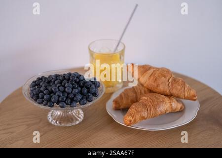 Frische Croissants mit Heidelbeeren und Orangensaft auf Holztisch Stockfoto