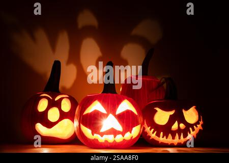 Halloween-Kürbisse mit gruseligen Gesichtern auf dunklem Hintergrund Stockfoto
