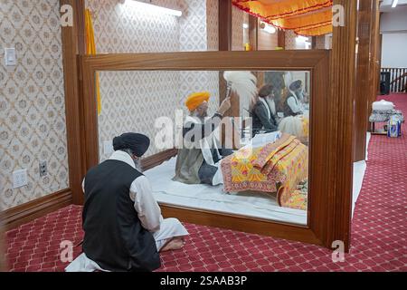 Auf einem Akhand-Pfad hören die Gläubigen den Sikh-Priestern zu, die das ganze Buch des Guru Granth Sahib lesen. In einem Tempel in New York. Stockfoto