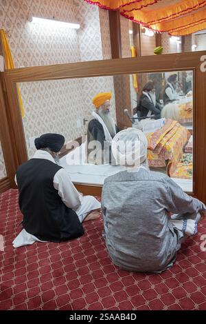 Auf einem Akhand-Pfad hören die Gläubigen den Sikh-Priestern zu, die das ganze Buch des Guru Granth Sahib lesen. In einem Tempel in New York. Stockfoto