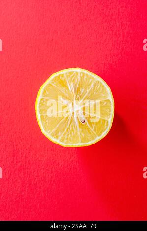 Stillleben einer geschnittenen Zitrone auf einem roten schwarzen Grund Stockfoto