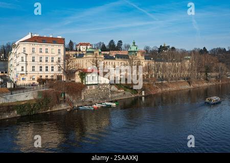 Linkes Ufer der Moldau in Prag mit der Mautstelle der ehemaligen Hängebrücke „Rudolfova lávka“ und dem Komplex „Strakova Akademie“, Regierungssitz. Stockfoto