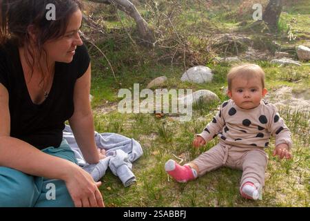 Zärtlicher Moment zwischen Mutter und ihrem kleinen Mädchen, das auf dem Gras sitzt Stockfoto