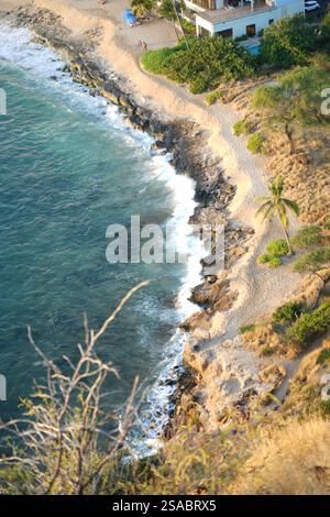 Aus der Vogelperspektive auf einen abgelegenen Strand mit türkisfarbenem Wasser und Palmen, Oahu, Hawaii – tropisches Paradies mit zerklüfteter Küste und Meereswellen. Stockfoto