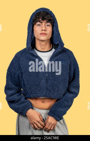 Modischer junger Mann mit blauem Pelzpullover und grauer Jogginghose mit ernsthaftem Ausdruck Stockfoto