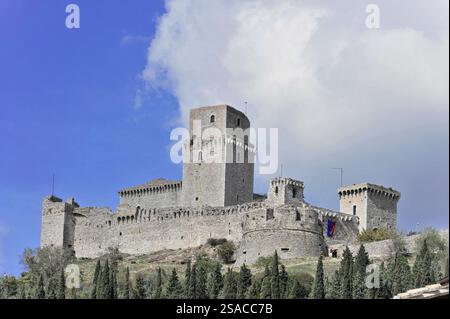 Schloss Rocca Maggiore in Assisi, Umbrien, Italien, Europa, große mittelalterliche Burg auf einem Hügel umgeben von Zypressen. Beeindruckend gegen einen teilweise bewölkten bl Stockfoto