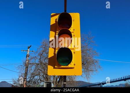 Bernsteinfarbene Ampel auf einer Baustelle an einem Tag mit blauem Himmel in Vancouver, BC. Stockfoto