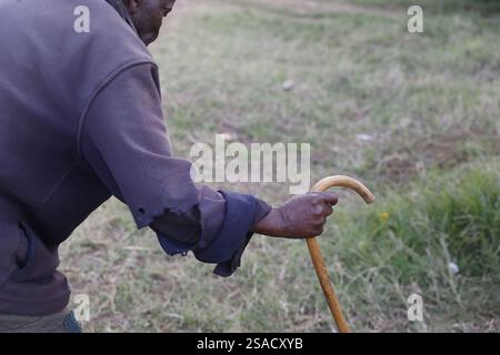 Älterer Wa-arusha-Mann, der mit einem Stock im Dorf N’giresi in Tansania spaziert. Stockfoto
