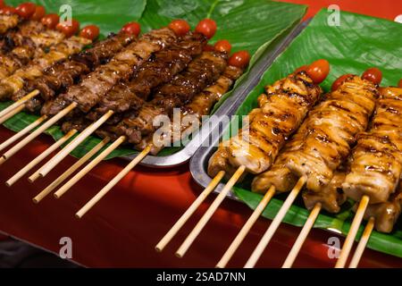 Auf der Thai Street Food Fair gab es leckere gegrillte Hühnchen- und Schweinespieße mit Tomate auf der Spitze. Ideal zum Kochen von Blogs, Restaurantmenüs und Stockfoto
