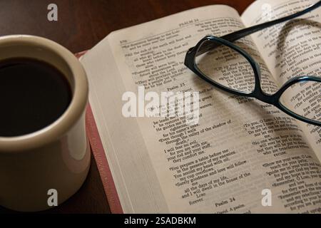 Morgendämmerung. Bibel offen für Psalm 23 mit Lesebläsern und einer Tasse Kaffee. Stockfoto