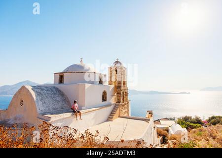 Junger Mann, der einen atemberaubenden Blick auf den Sonnenuntergang von der traditionellen weiß getünchten griechisch-orthodoxen Kirche im Dorf Plaka auf der Insel Milos genießt Stockfoto