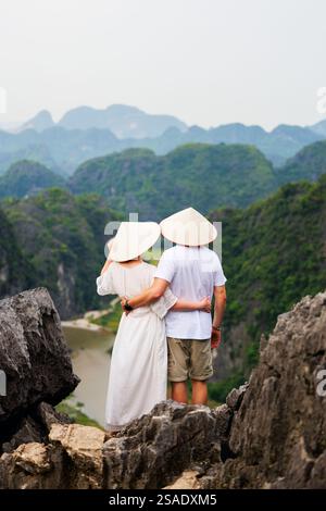 Ein wunderschönes Paar reist gerne durch Südostasien und betrachtet die Aussicht auf die Karstberge und den Fluss der Mua Cave in Vietnam Stockfoto