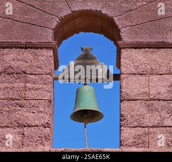 Offener Glockenturm mit grüner Glocke in einer roten Steinfassade Stockfoto