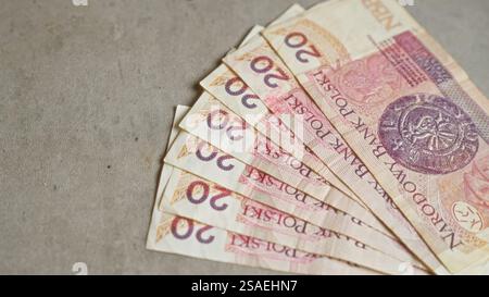 Polnische Banknoten im Wert von 20 Zloty, die auf einer Betonoberfläche verteilt sind und die mit polen verbundene Finanzwährung und Wirtschaft darstellen. Stockfoto