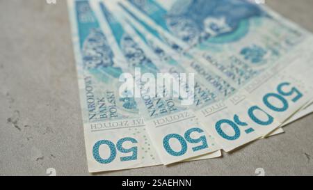 Polnische Banknoten im Wert von 50 Zloty sind auf einer Betonoberfläche mit verschiedenen Stückelungen verteilt. Stockfoto