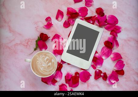 Romantische Komposition mit einer Tasse Kaffee, Rosenblättern und E-Reader mit Kopierraum auf rosa Marmorhintergrund. Vorlage für feminine Blogs. Stockfoto
