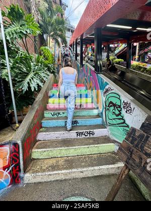 Ein Mädchen, das eine Regenbogentreppe in der Comuna 13 in Medellin, Kolumbien, aufsteigt Stockfoto