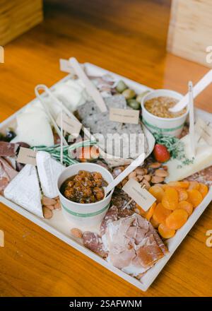 Eine wunderschön angeordnete Wurstplatte mit verschiedenen Wurstwaren, Käse, Nüssen, getrockneten Früchten und Gewürzen auf einer polierten Holztabelle Stockfoto