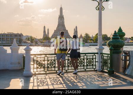 Während die Sonne über dem majestätischen Wat Arun in Bangkok untergeht, stehen ein Paar Hand in Hand und genießen die atemberaubende Landschaft. Stockfoto