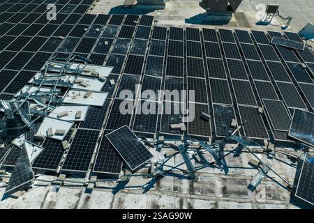 Draufsicht der durch den Hurrikan Ian zerstörten Photovoltaik-Solarpaneele, die auf dem Dach des Industriebaues zur Erzeugung von ökologischem Strom montiert sind Stockfoto