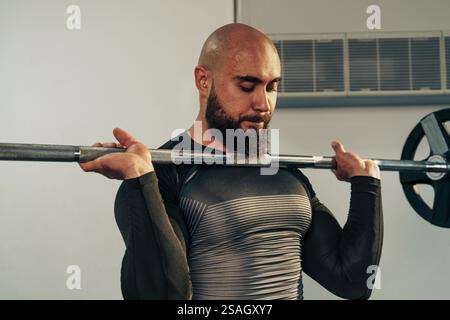 Strong man hebt Langhantel in einem Fitnessstudio während des Krafttrainings, um Muskeln aufzubauen und die Fitness zu verbessern Stockfoto