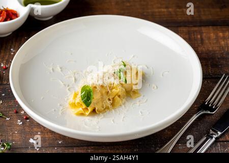 Köstliche italienische Pasta Pappardelle mit Parmesan auf weißem Porzellanteller auf Holztisch Stockfoto