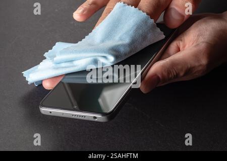 Keimeliminierung. Reinigen Sie den Bildschirm des Smartphones mit einem Fasertuch von Schmutz, Staub und anderen äußeren Einflüssen. Mobile Care-Konzept Stockfoto