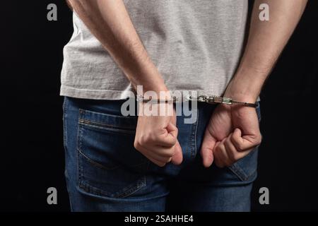 Verhafteter Mann in Handschellen mit Handschellen hinten im Gefängnis. Stockfoto