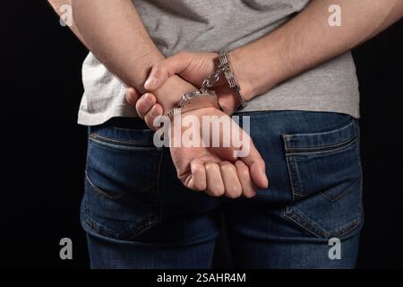 Verhafteter Mann in Handschellen mit Handschellen hinten im Gefängnis. Stockfoto
