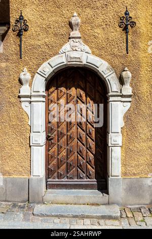Vorderansicht der geschnitzten hölzernen Eingangstür eines mittelalterlichen Stadthauses in einer Kopfsteinpflasterstraße der Altstadt von Stockholm, Schweden. Stockfoto