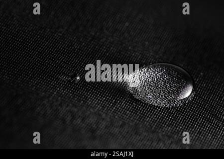 Wassertropfen auf wasserdichtem schwarzem Material. Stockfoto