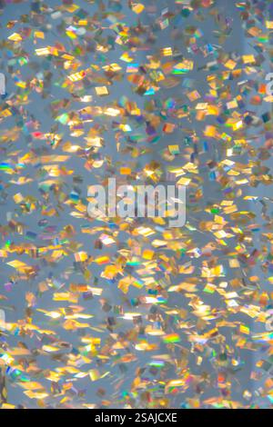 Glitzereffekt mit kleinen bunten Partikeln auf gedämpftem Hintergrund, Unschärfe Stockfoto