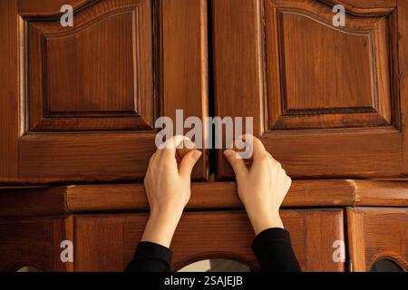 Frau Hand öffnet alten Holzschrank im Schlafzimmer zu Hause, alte Möbel Stockfoto